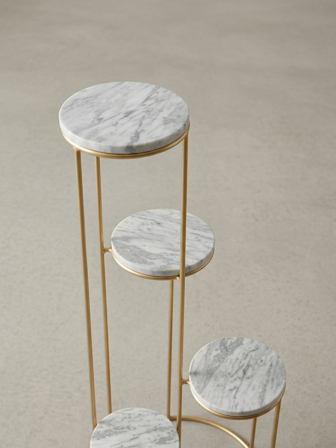 Nahaufnahme der Verbindung zwischen dem goldenen Eisengestell und einer der weißen Marmorplatten des exklusiven Blumenhockers._