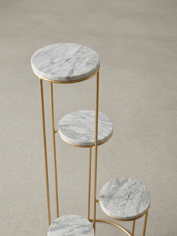 Nahaufnahme der Verbindung zwischen dem goldenen Eisengestell und einer der weißen Marmorplatten des exklusiven Blumenhockers._