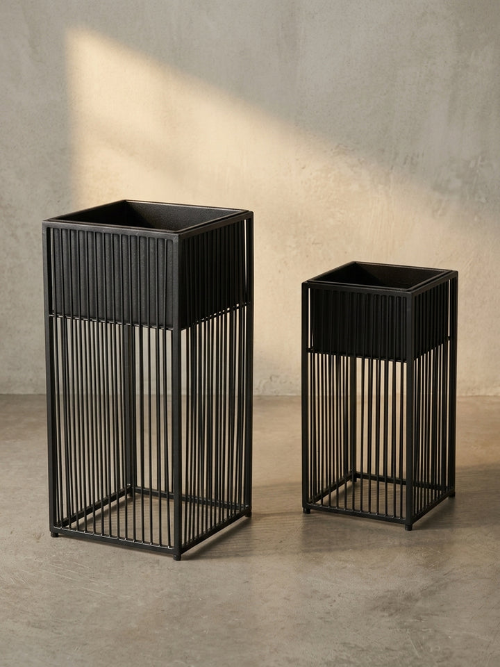 Schräge 3/4-Ansicht des schwarzen Metall-Blumentopf-Sets, die die Tiefe des Designs und die Konstruktion des offenen Gestells und des abnehmbaren Pflanzkastens verdeutlicht._
