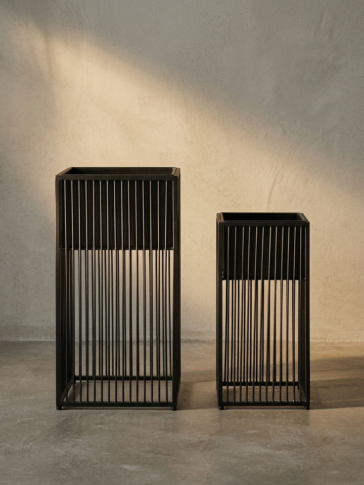 Das komplette 2er Set schwarzer Pflanzkübel aus Eisen, die durch ihre geometrische Form und das Spiel von massiven und offenen Flächen bestechen._