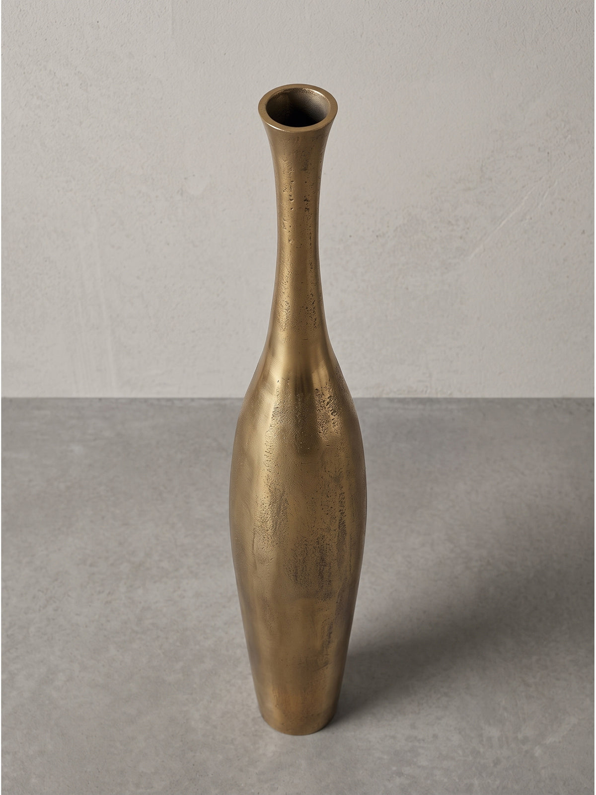 Luxuriöse Dekovase aus Metall in eleganter Tropfenform mit schmaler Öffnung von leicht schräg vorn im hellen Fotostudio porträtiert.
