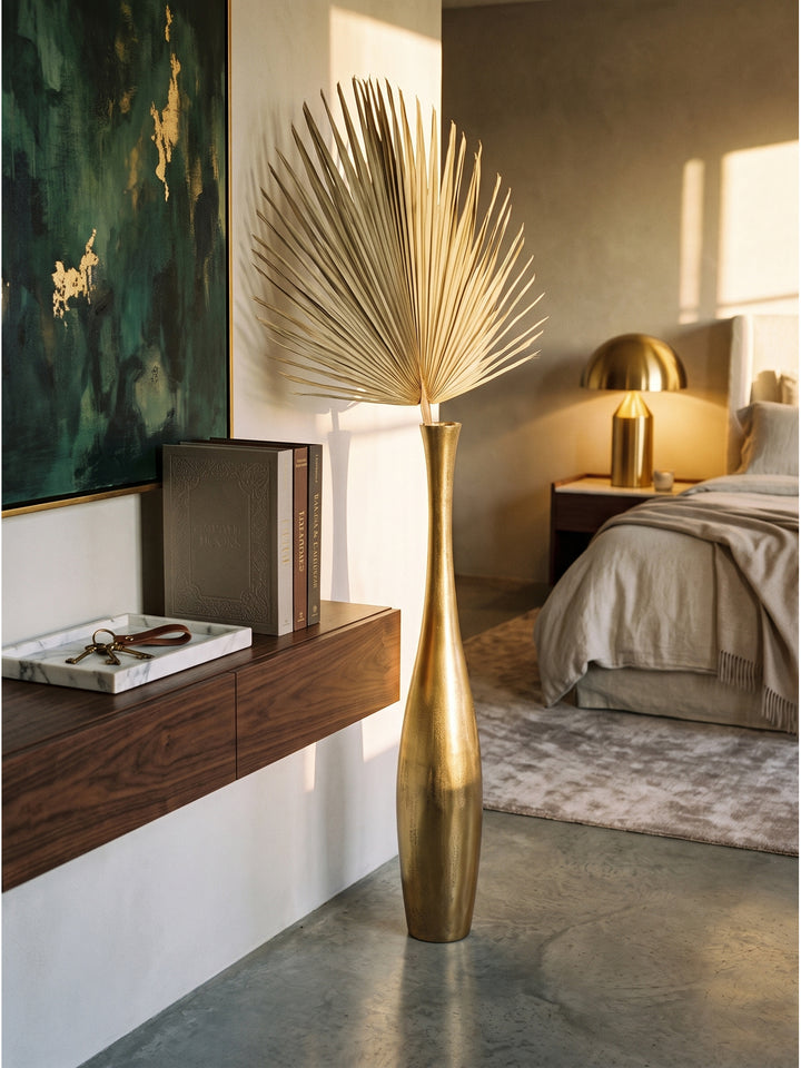 Schmale goldene Bodenvase mit getrocknetem Zweig neben dunklem Konsolentisch und Marmortablett im Flur_