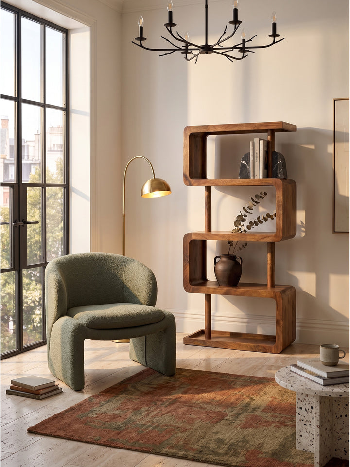 Massives Mangoholz Bücherregal im Vintage-Modern Stil arrangiert neben einem salbeigrünen Bouclé-Sessel auf einem hellen Berberteppich_