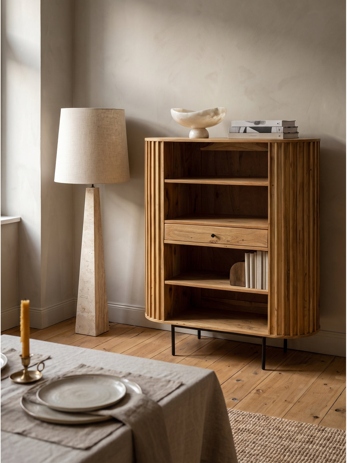 Dekoratives offenes Bücherregal aus Holz mit einer Schublade, bestückt mit Büchern und einer Keramikschale vor einer dezenten Kalkfarbe-Wand._