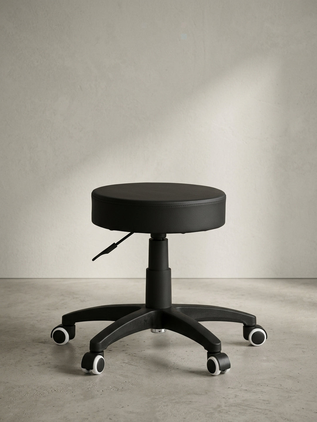 Schwarzer Kosmetikhocker in angewinkelter Perspektive fotografiert, zeigt das puristische und rein auf Funktion reduzierte Design, welches perfekt für den professionellen Arbeitsalltag ist._