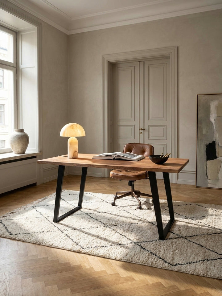 Ein eleganter Home-Office-Arbeitsplatz mit dem massiven Akazienholz-Schreibtisch im Zentrum, auf einem beigen Wollteppich vor einer kalkgewaschenen Wand._