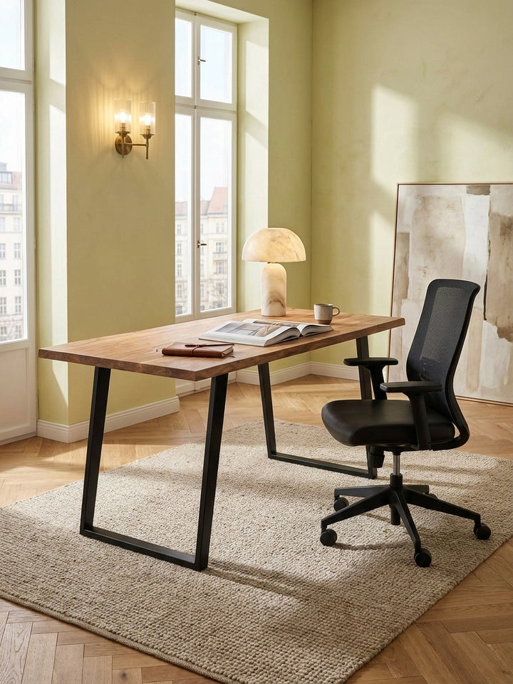 Der Holztisch mit schwarzen Metallbeinen kombiniert mit einem modernen, schwarzen Netz-Bürostuhl, der perfekt unter die 76 cm hohe Tischplatte passt._