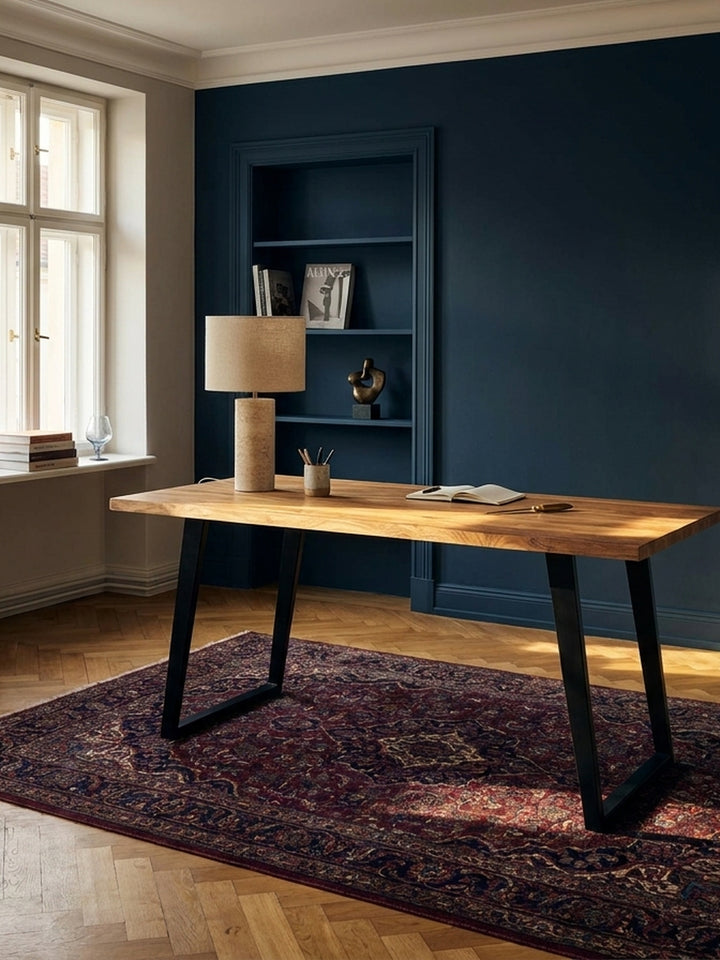 Ein stilvoller Schreibtisch aus Akazie Massivholz in einem eleganten Homeoffice mit dunkelblauer Wand und Fischgrätparkett._