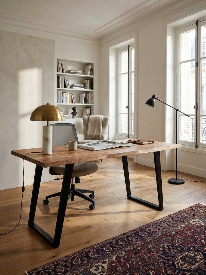 Der Massivholz-Schreibtisch mit Baumkante kombiniert mit einem ergonomischen Bürostuhl aus schwarzem Leder vor einer texturierten Kalkputzwand im Arbeitszimmer._