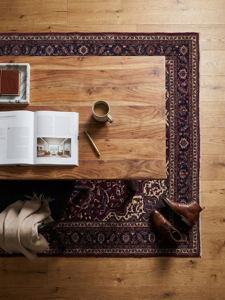 Aufsicht auf einen Homeoffice-Arbeitsplatz mit dem Akazien-Schreibtisch als Zentrum, umgeben von einem Ledersessel und Bücherregalen in einem stilvollen Altbau-Arbeitszimmer._