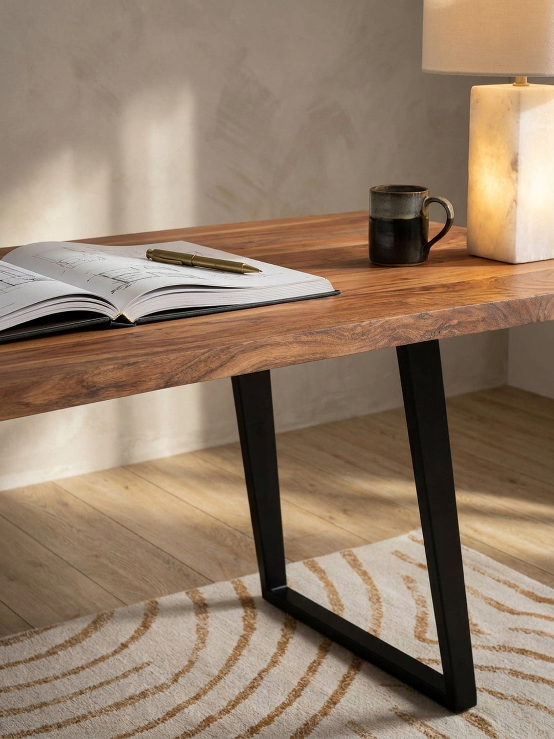 Detailansicht des Akazienholz-Schreibtisches mit einem aufgeschlagenen Architekturbuch und einer Tasse Kaffee, was eine konzentrierte Arbeitsatmosphäre im Homeoffice schafft._