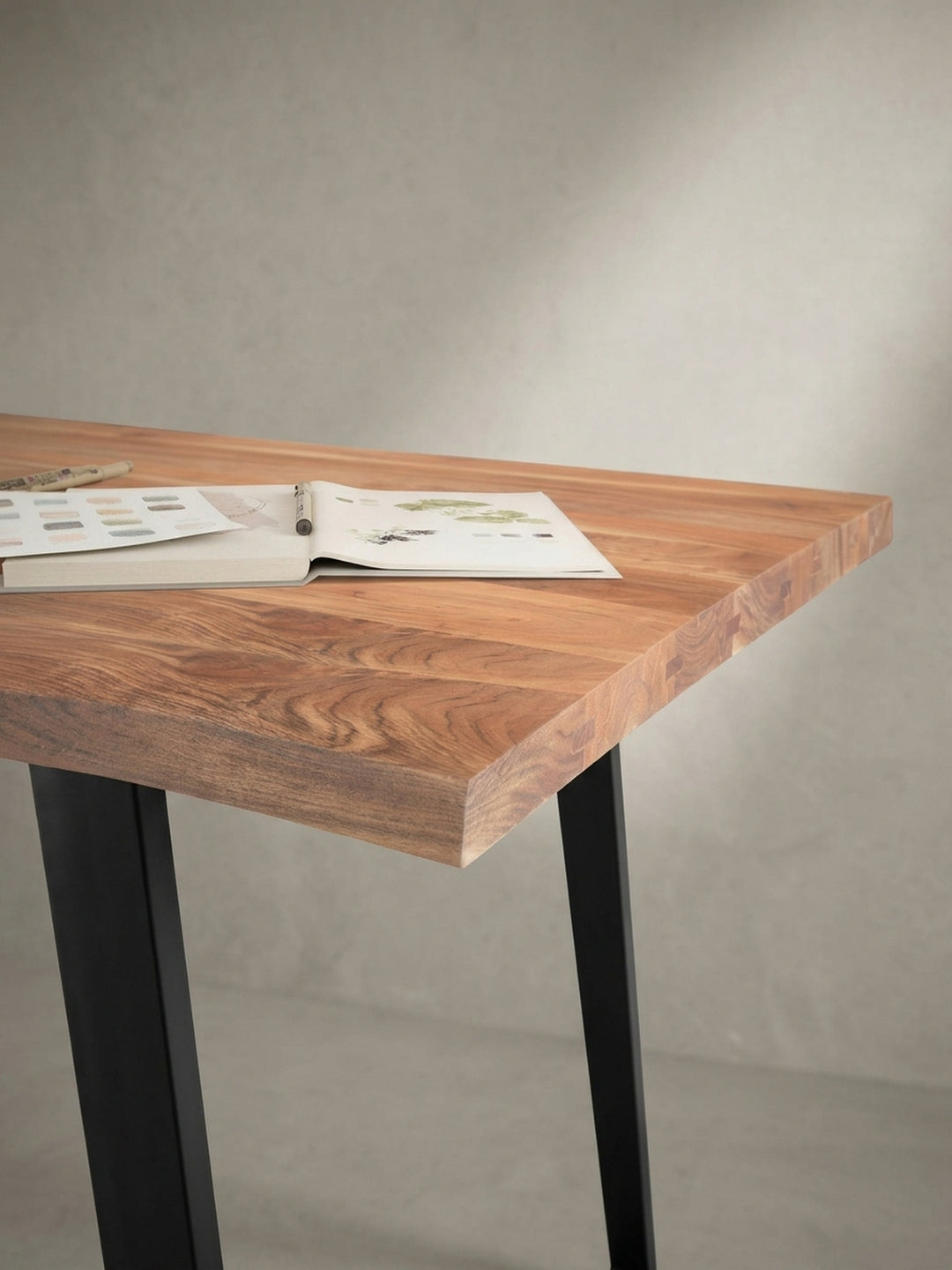 Alternative Perspektive des Homeoffice-Tisches, die den Kontrast zwischen dem warmen Akazienholz und dem kühlen, mattschwarzen Metallgestell betont._