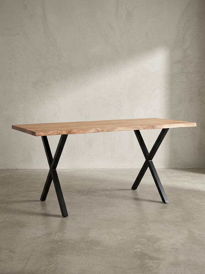 Freigestellter Schreibtisch aus Akazienholz mit charakteristischer Baumkante und stabilen, schwarzen Metallbeinen in X-Form aus einer frontalen Perspektive._