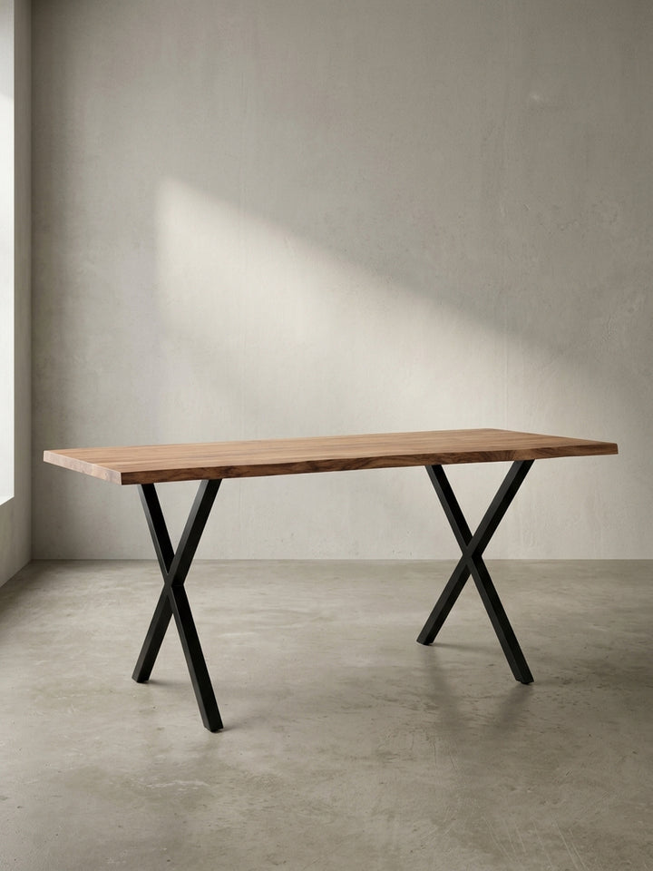 Moderner Schreibtisch 140x80 cm aus massivem Akazienholz mit charakteristischer Baumkante und schwarzen Metall-X-Beinen freigestellt._