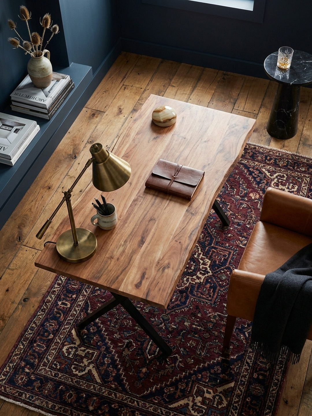 Draufsicht auf einen modernen Holztisch im Homeoffice, der mit Laptop und Büchern auf einem hellen Holzboden mit cremefarbenem Teppich arrangiert ist, was die kompakte Größe zeigt._