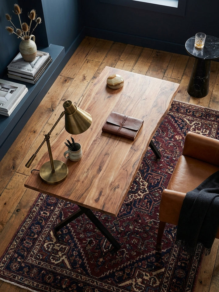 Draufsicht auf einen modernen Holztisch im Homeoffice, der mit Laptop und Büchern auf einem hellen Holzboden mit cremefarbenem Teppich arrangiert ist, was die kompakte Größe zeigt._
