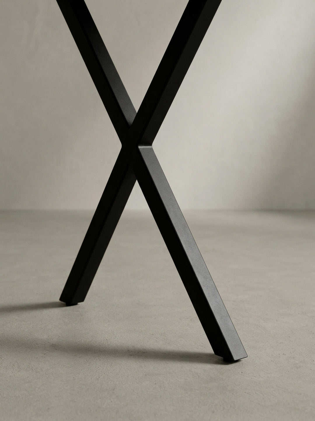 Nahaufnahme des industriellen Designs der schwarzen, pulverbeschichteten X-Beine des Akazie Massivholz-Schreibtischs, ein Detail für moderne Büros._