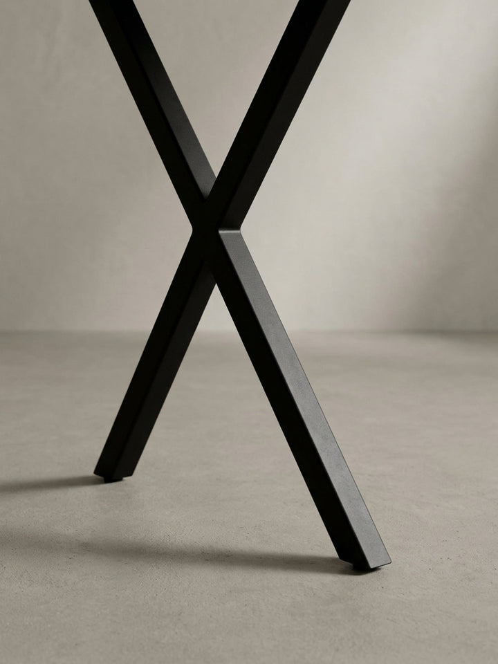 Nahaufnahme des industriellen Designs der schwarzen, pulverbeschichteten X-Beine des Akazie Massivholz-Schreibtischs, ein Detail für moderne Büros._