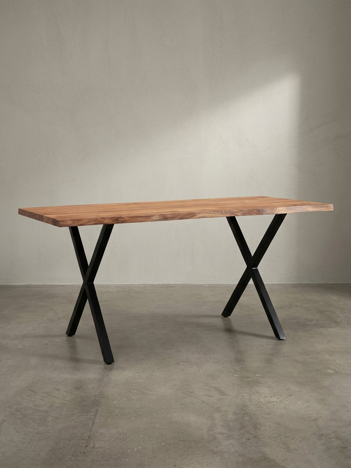 Design-Schreibtisch aus massivem Akazienholz mit einzigartiger Baumkante und schwarzen Metall-X-Beinen als repräsentatives Möbelstück fürs Homeoffice._