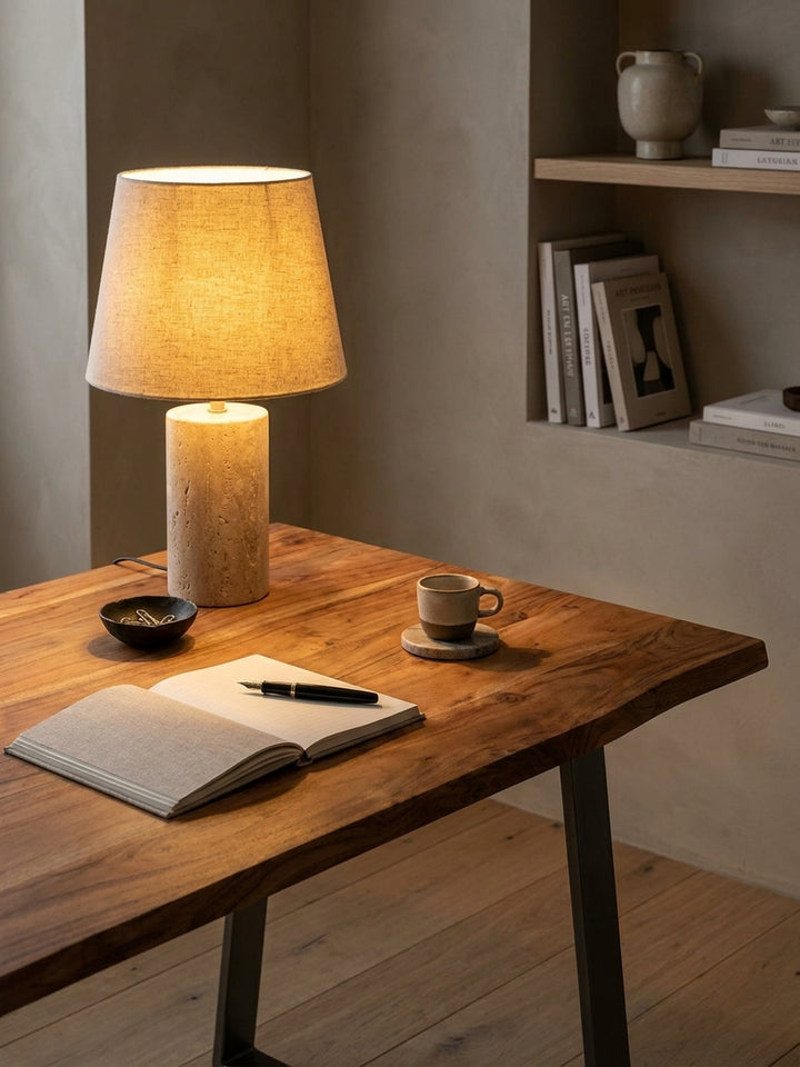 Einrichtungsidee für das Arbeitszimmer: Schreibtisch mit Baumkante, darauf ein Notizbuch und eine Design-Tischlampe._