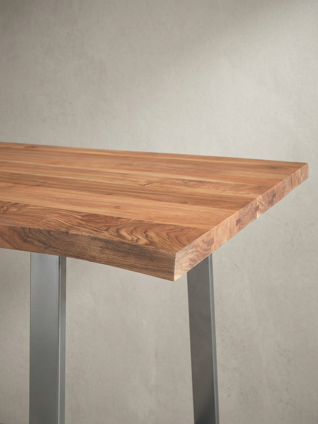 Eine alternative Perspektive des Holztisches für das Homeoffice, die das Zusammenspiel von natürlicher Baumkante und industriellem Gestell betont._