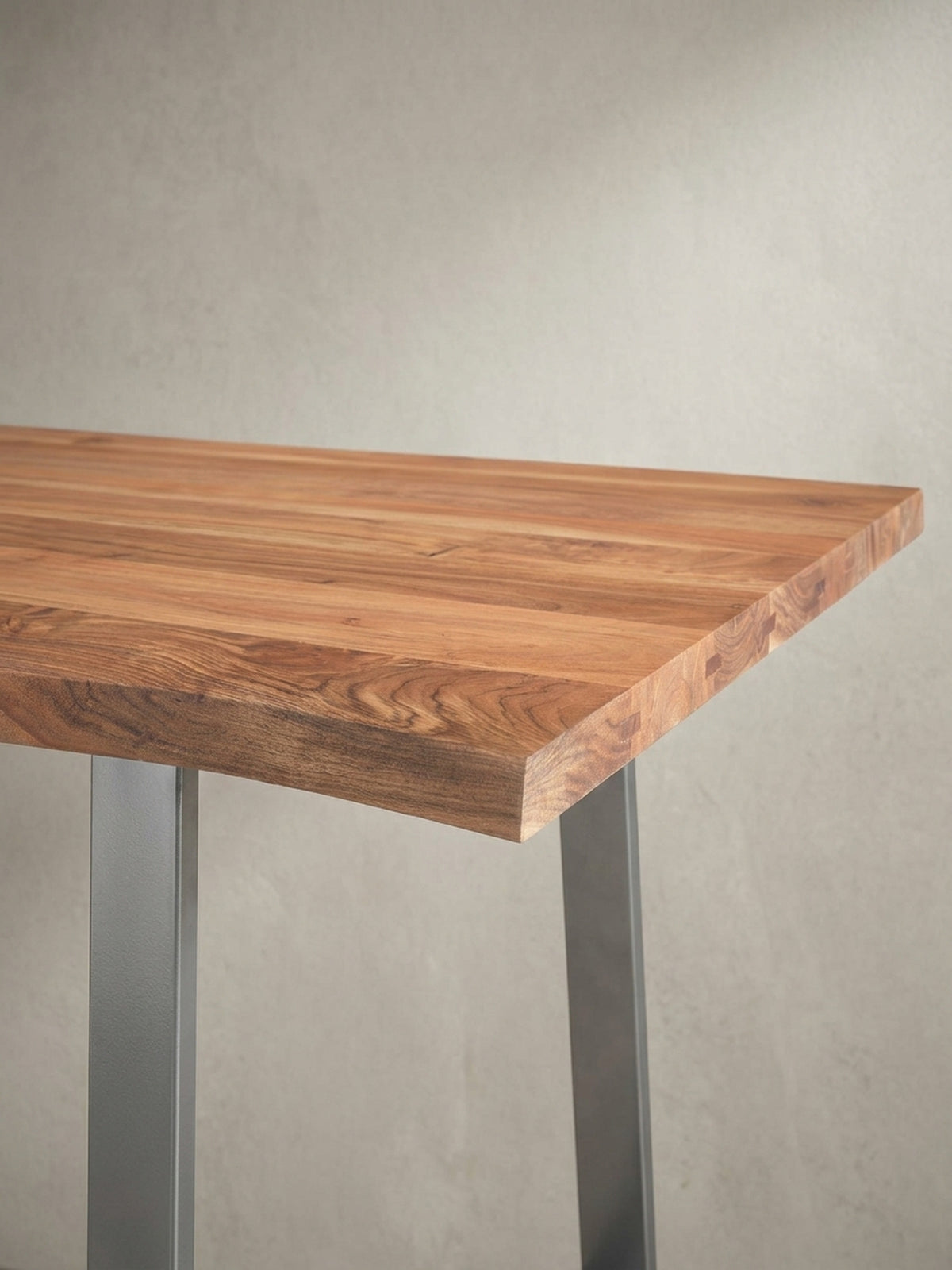 Eine alternative Perspektive des Holztisches für das Homeoffice, die das Zusammenspiel von natürlicher Baumkante und industriellem Gestell betont.