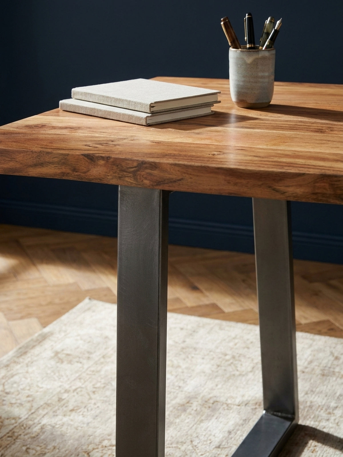 Detailaufnahme der lebendigen Maserung und der warmen Farbe des Akazienholzes der Schreibtischplatte mit Klarlack-Finish.