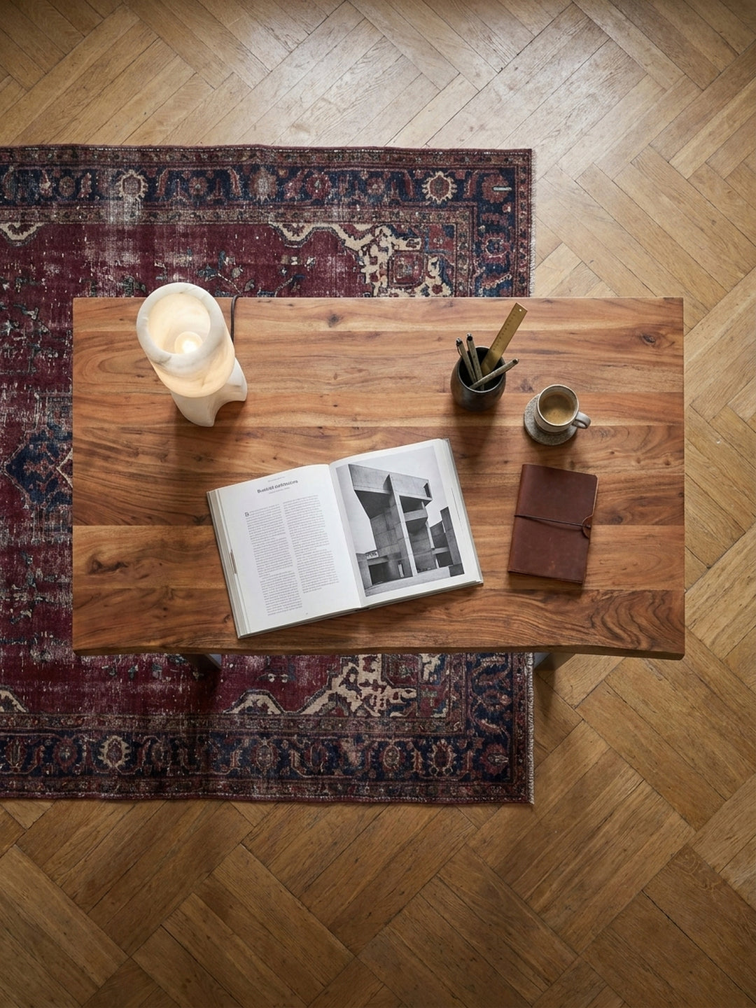 Draufsicht auf einen 200x100 cm Schreibtisch aus Akazienholz mit Metallbeinen, arrangiert auf einem Vintage-Perserteppich im Arbeitszimmer._
