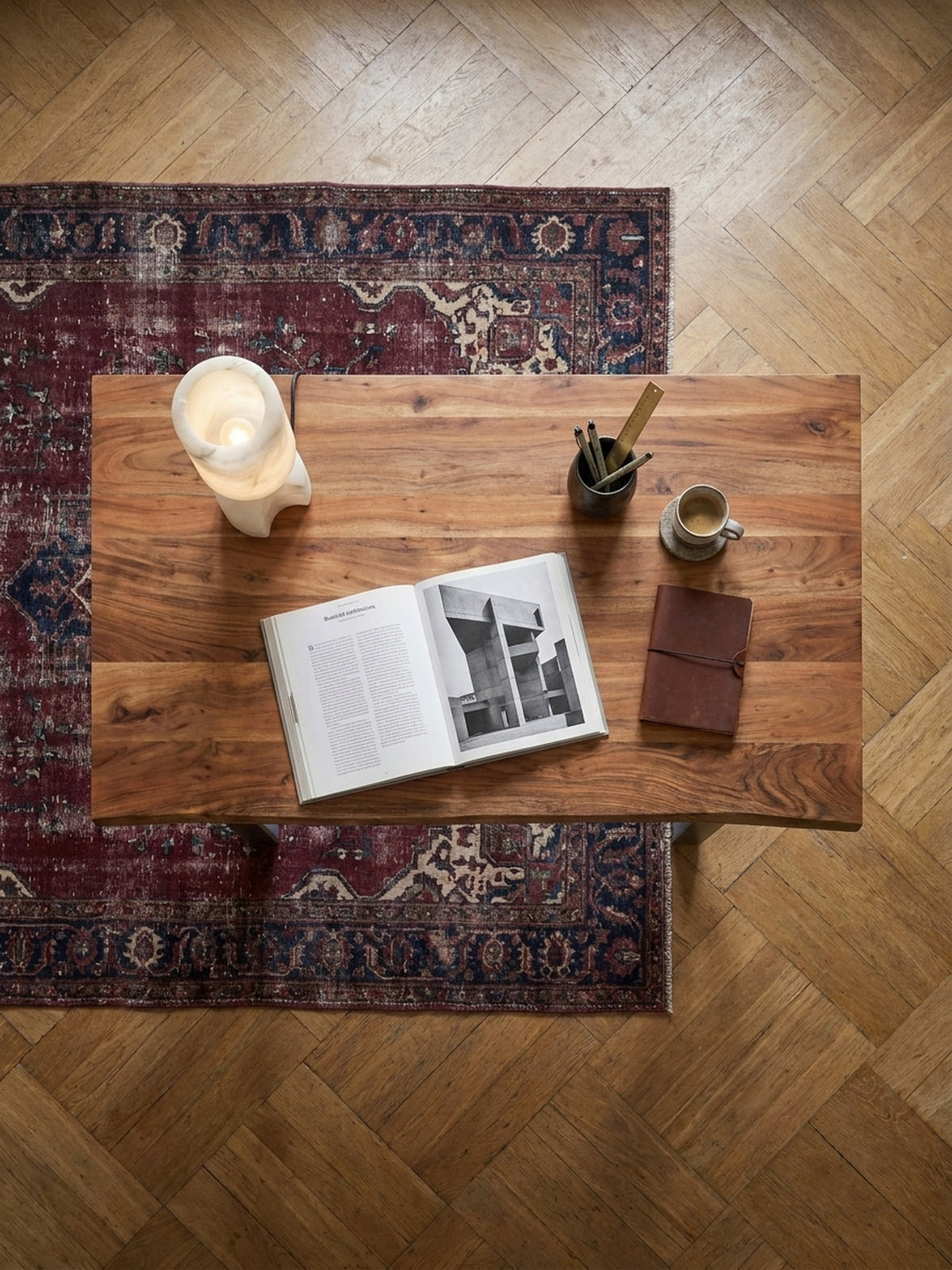 Draufsicht auf einen 200x100 cm Schreibtisch aus Akazienholz mit Metallbeinen, arrangiert auf einem Vintage-Perserteppich im Arbeitszimmer.