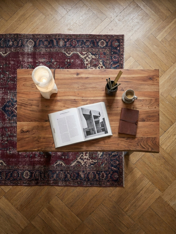 Draufsicht auf einen 200x100 cm Schreibtisch aus Akazienholz mit Metallbeinen, arrangiert auf einem Vintage-Perserteppich im Arbeitszimmer._