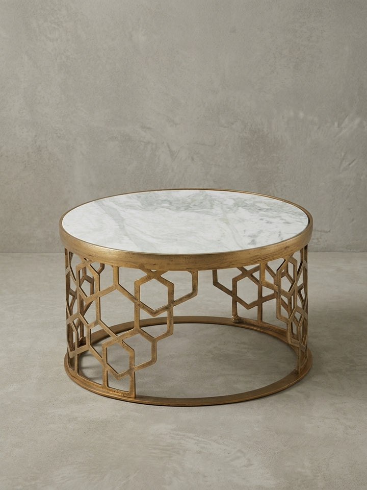 Der runde Marmor-Couchtisch aus einer alternativen Perspektive, die das Lichtspiel auf der polierten Marmoroberfläche und dem satinierten Gold-Finish des Gestells einfängt._