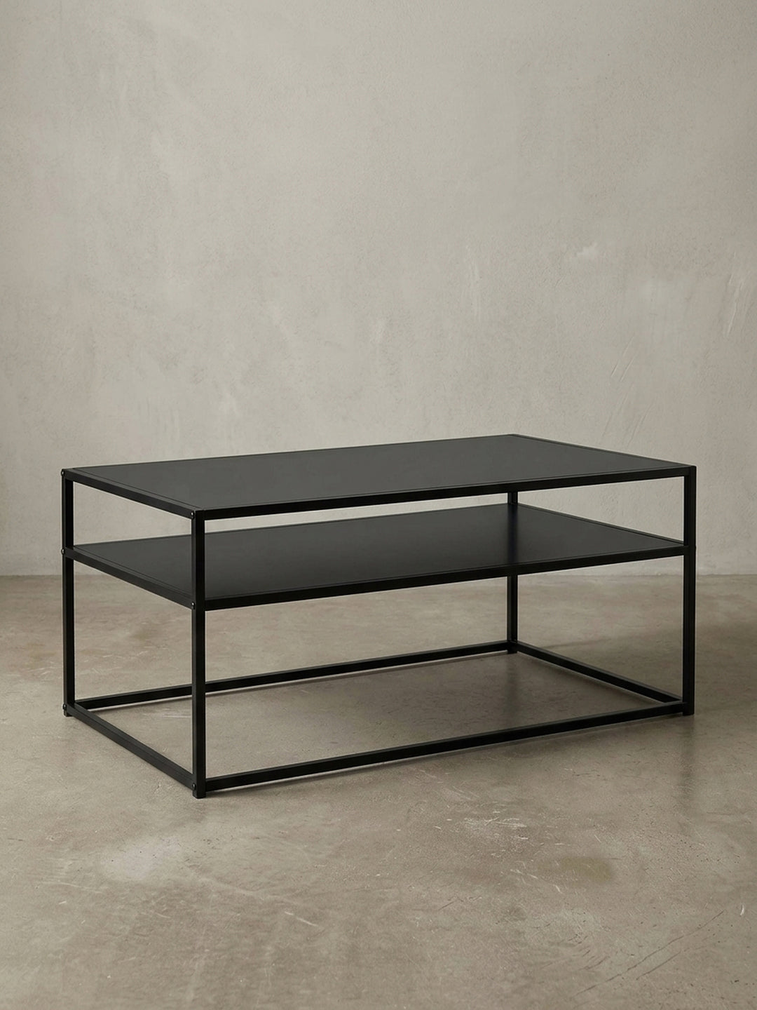 3/4-Ansicht des schwarzen Metall-Couchtisches, der die offene, luftige Konstruktion und die Stärke des 1,5 cm dicken Stahlrahmens elegant zur Geltung bringt._