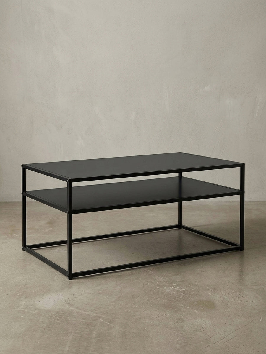 3/4-Ansicht des schwarzen Metall-Couchtisches, der die offene, luftige Konstruktion und die Stärke des 1,5 cm dicken Stahlrahmens elegant zur Geltung bringt._