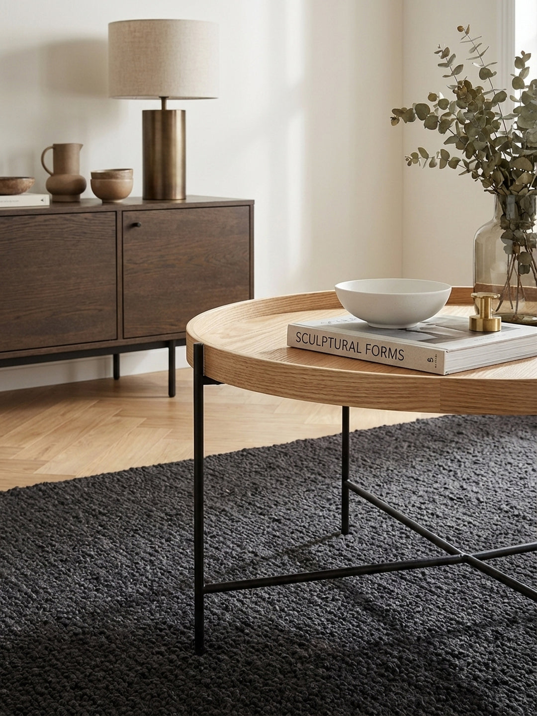Detailaufnahme der hochwertigen Eichenholz-Furnieroberfläche des runden Couchtischs, die feine Maserung und die warme, natürliche Textur des Holzes betonend._