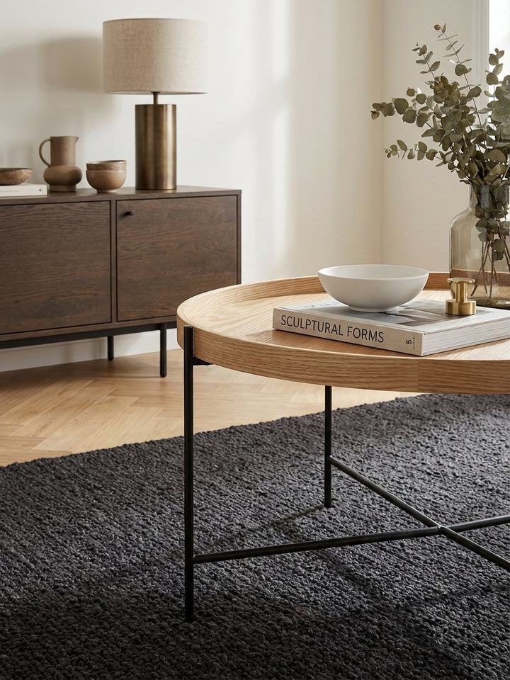 Detailaufnahme der hochwertigen Eichenholz-Furnieroberfläche des runden Couchtischs, die feine Maserung und die warme, natürliche Textur des Holzes betonend._