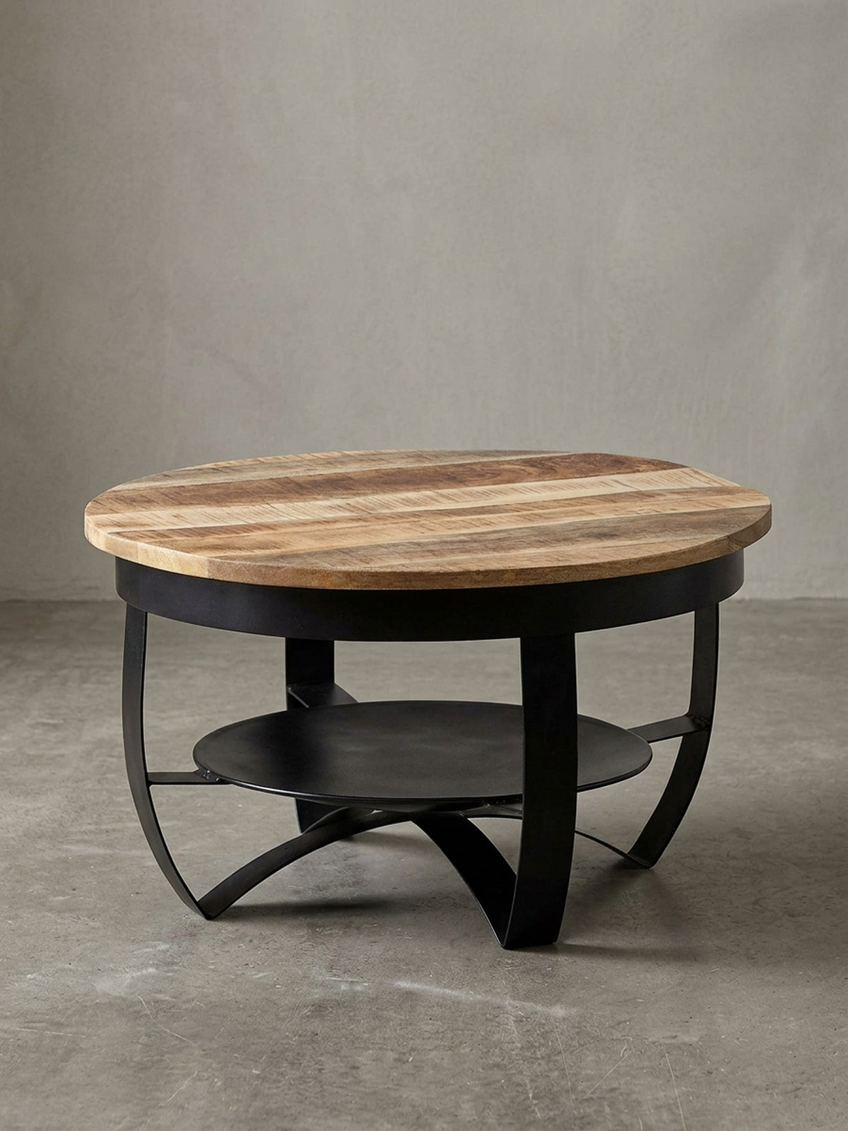Freigestellter Couchtisch im Industrial-Stil, runde Form, mit Tischplatte aus Mango-Massivholz und schwarzem Metallgestell, Frontansicht._