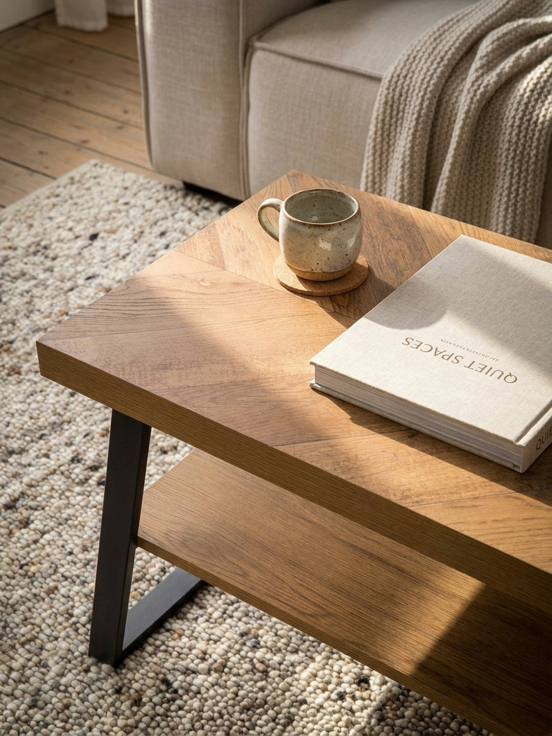 Industrieller Loungetisch mit schwarzen Metallbeinen, platziert auf einem beigen Teppich vor einem Sofa in einem gemütlichen Wohnambiente._