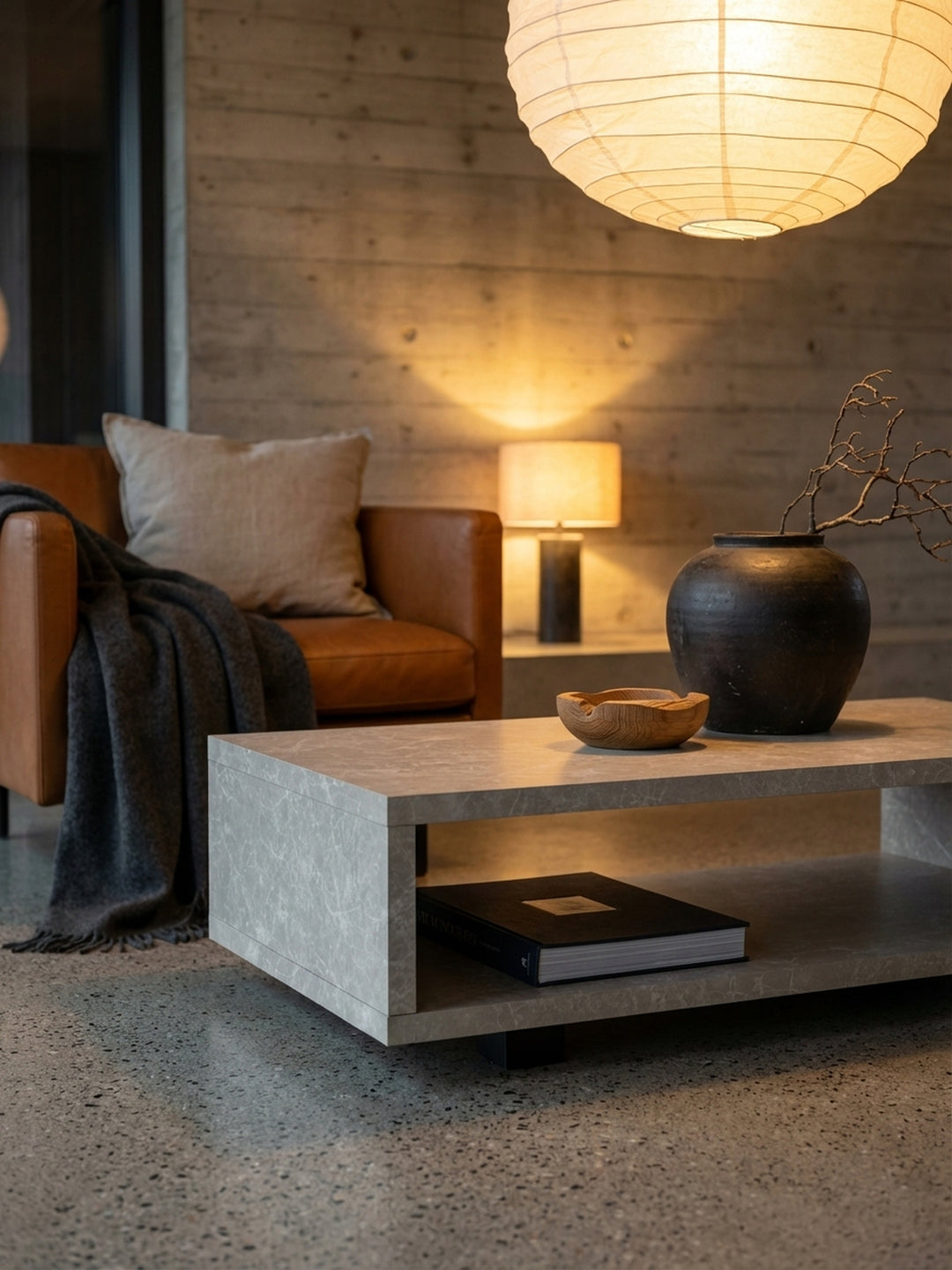 Dekoratives Stillleben auf dem beigen Sofatisch: Eine Keramikvase mit Trockenblumen und eine Tasse Kaffee schaffen eine gemütliche Atmosphäre._