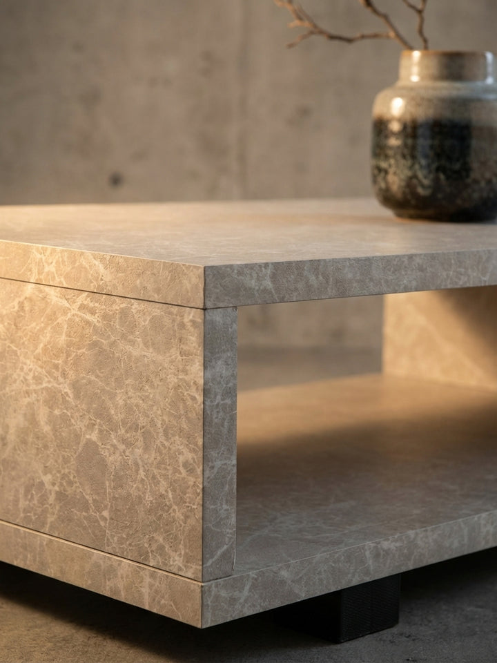Nahaufnahme der sandfarbenen Oberfläche des Couchtisches, die eine feine, marmorierte Stein-Optik und eine matte Textur zeigt._