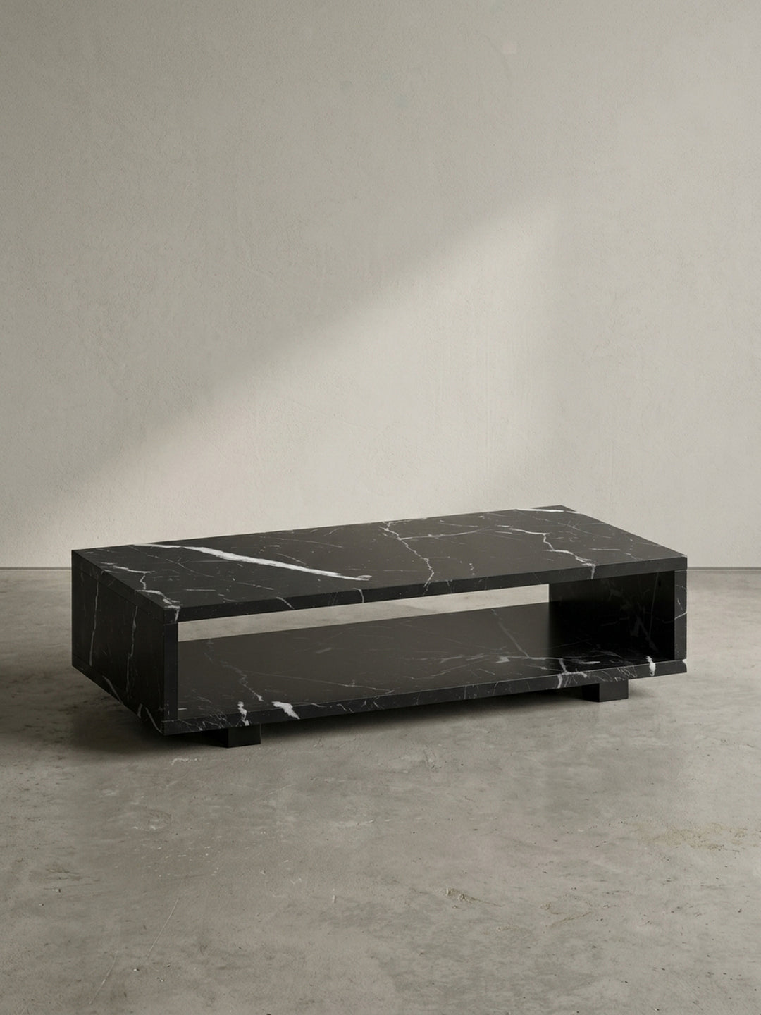 Vorderansicht des rechteckigen Couchtisches 100x50x25 cm aus schwarzem MDF mit Marmordekor, schwebend durch verdeckte Füße vor neutralem weißen Hintergrund_