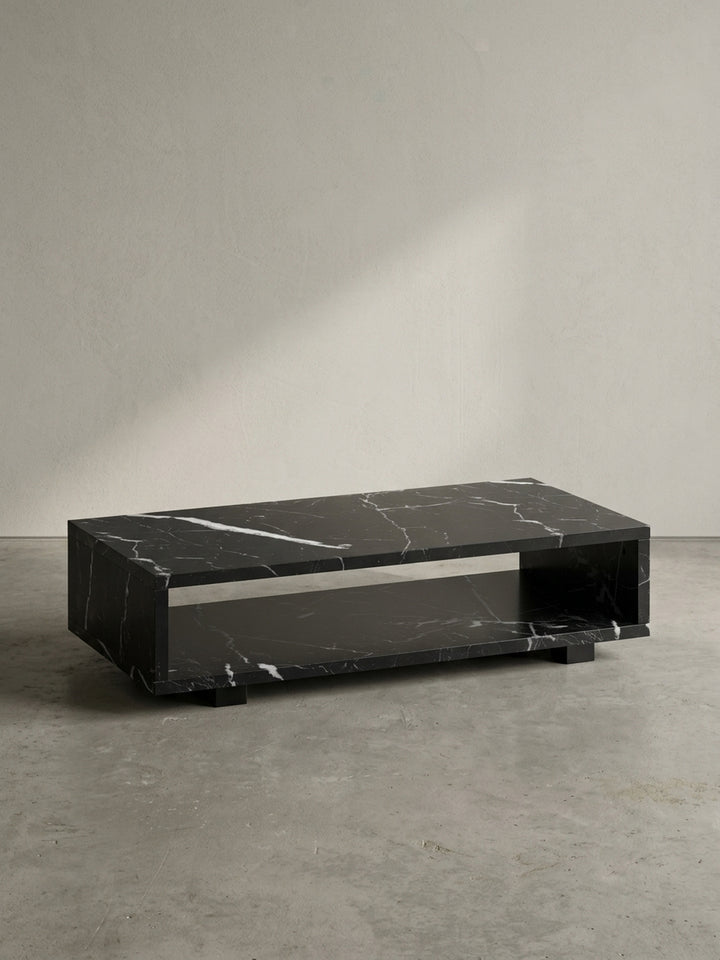 Vorderansicht des rechteckigen Couchtisches 100x50x25 cm aus schwarzem MDF mit Marmordekor, schwebend durch verdeckte Füße vor neutralem weißen Hintergrund_