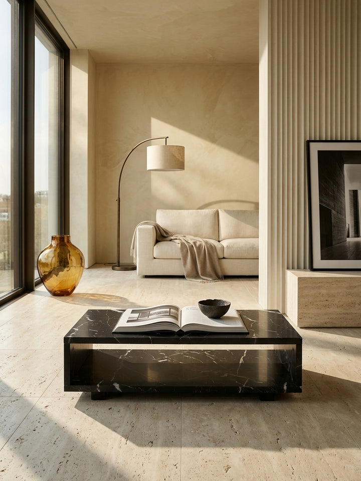 Moderner schwarzer Couchtisch in Marmor-Optik 100x50x25 cm als zentrales Element im minimalistischen Wohnzimmer mit bodentiefen Fenstern auf glattem Kalksteinboden_