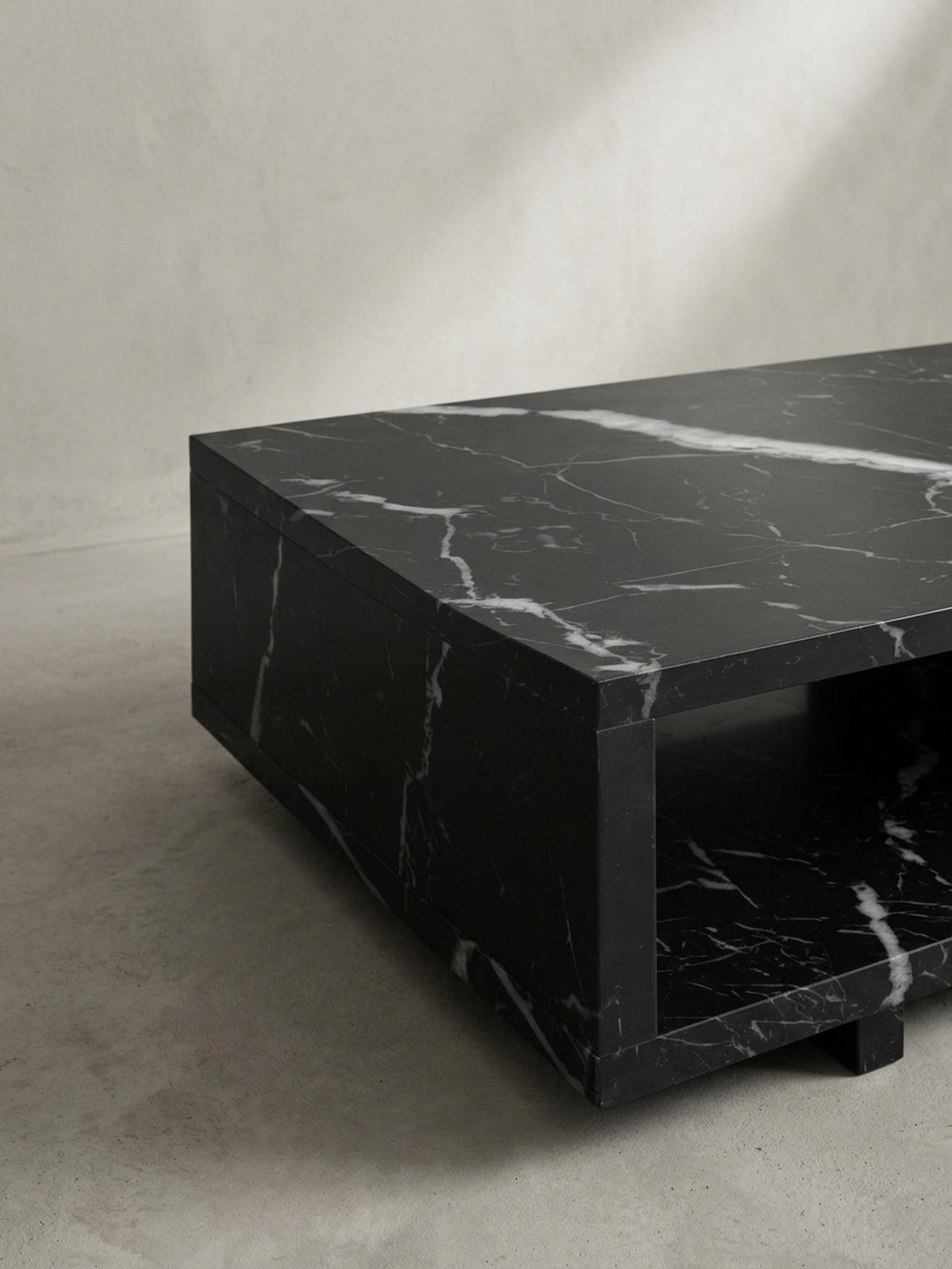Alternative Studioansicht des kompakten Sofatisches, die das spannende Zusammenspiel von massiver Form und elegantem schwarzem Hochglanzfinish hervorhebt_