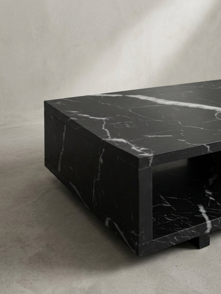 Alternative Studioansicht des kompakten Sofatisches, die das spannende Zusammenspiel von massiver Form und elegantem schwarzem Hochglanzfinish hervorhebt_