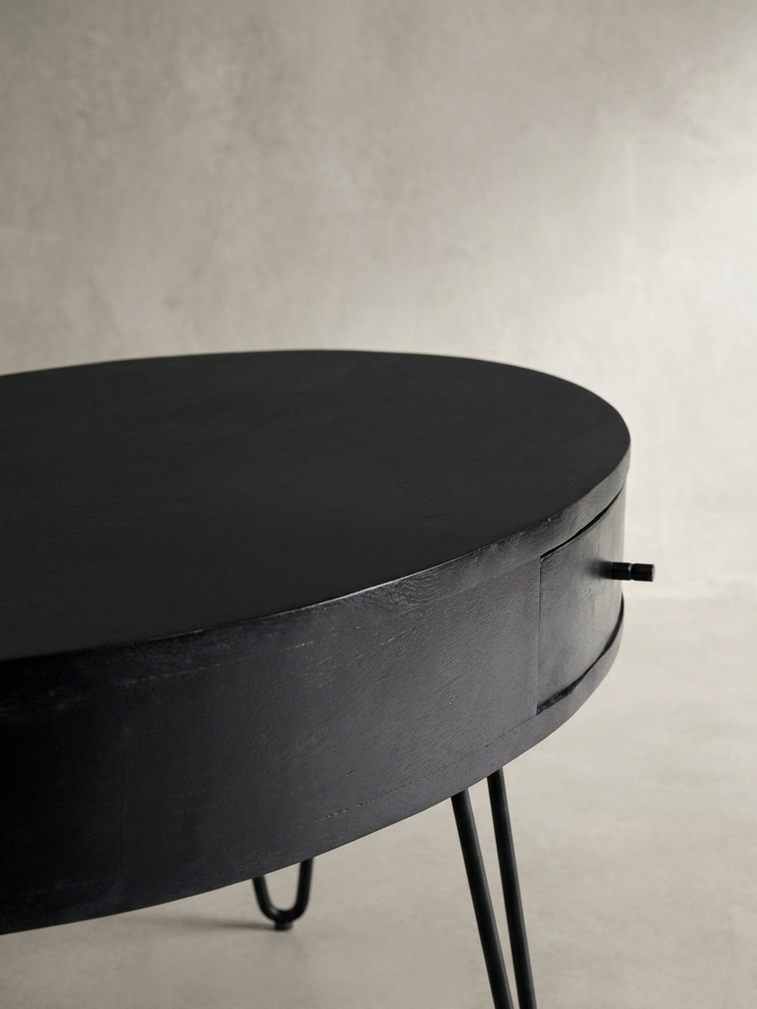 Eine alternative Perspektive auf den Kaffeetisch, die die Tiefe der Schublade und die elegante Rundung der ovalen Tischplatte einfängt._