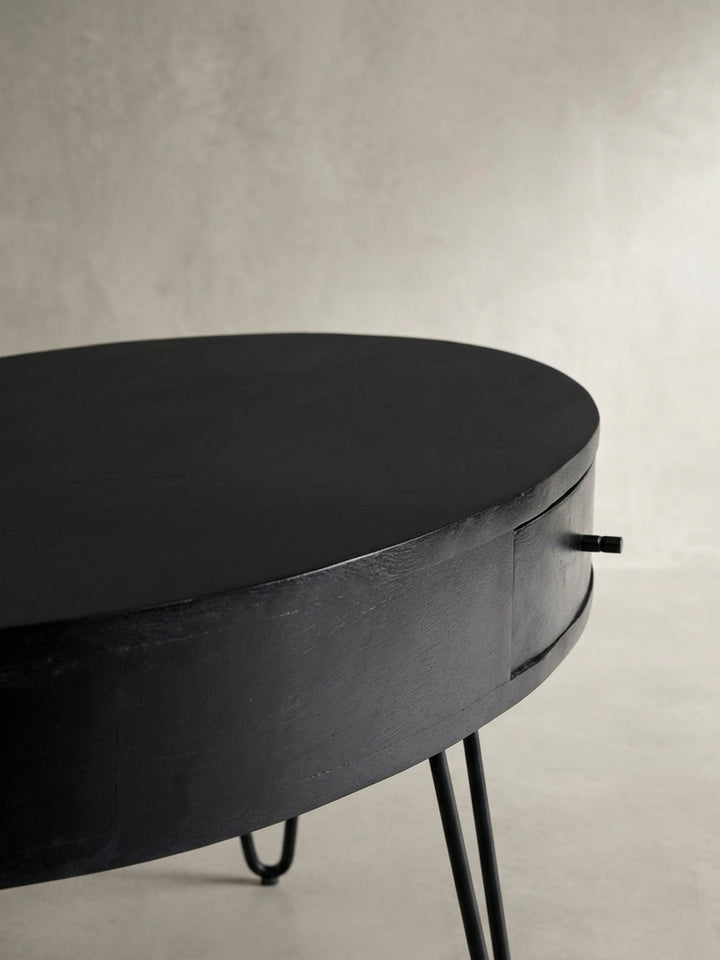 Eine alternative Perspektive auf den Kaffeetisch, die die Tiefe der Schublade und die elegante Rundung der ovalen Tischplatte einfängt._