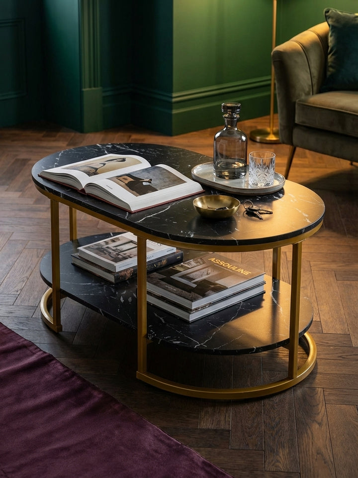 Styling-Detail auf dem modernen Sofatisch: ein schweres Kunstbuch und ein Kristall-Whiskyglas auf der schwarzen Marmor-Oberfläche, was eine gemütliche Abendstimmung erzeugt._
