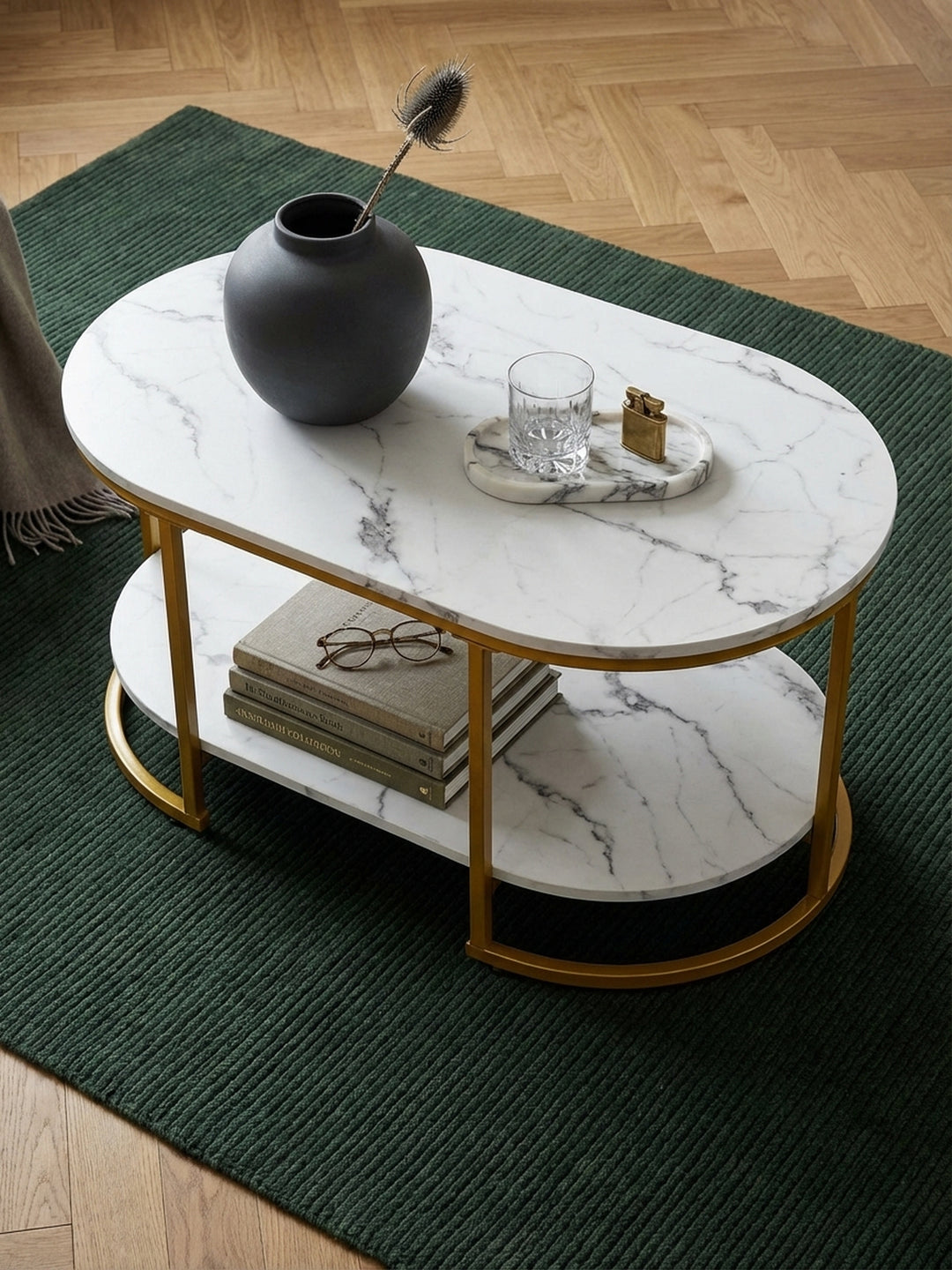 Design-Couchtisch mit goldenem Gestell und Ablage, von oben fotografiert auf einem cremefarbenen Teppich vor einer Couch._