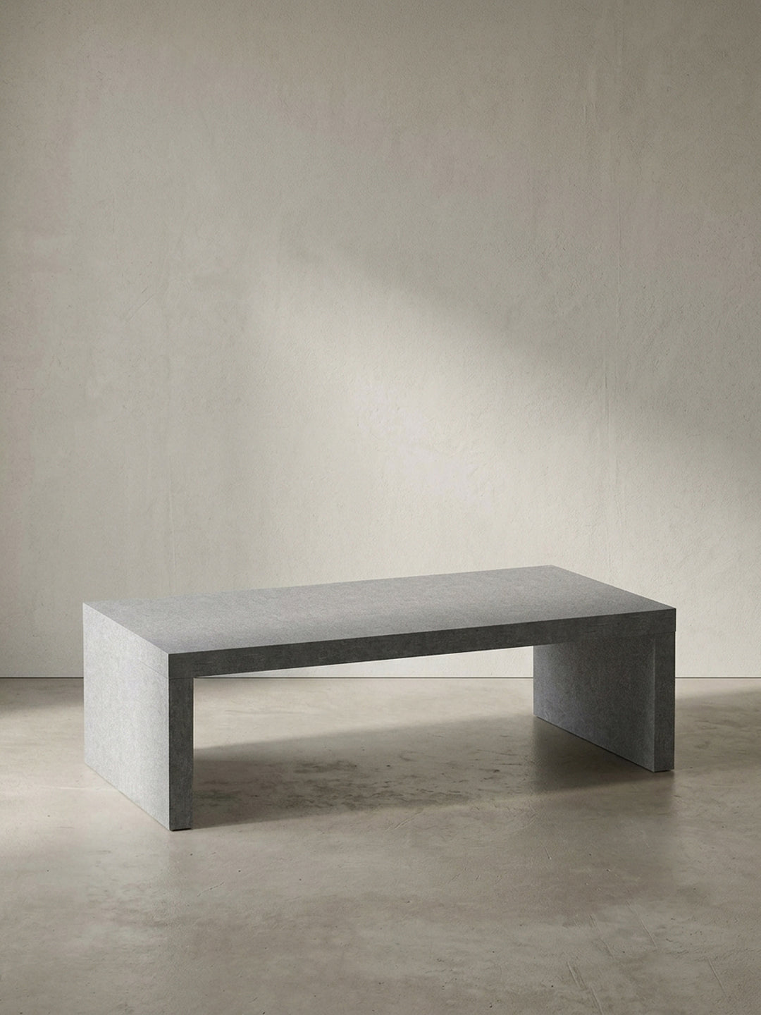 Grauer Couchtisch in klarer Beton-Optik mit den kompakten Maßen 110x55x35 cm frontal vor einem neutralen, reinweißen Hintergrund_