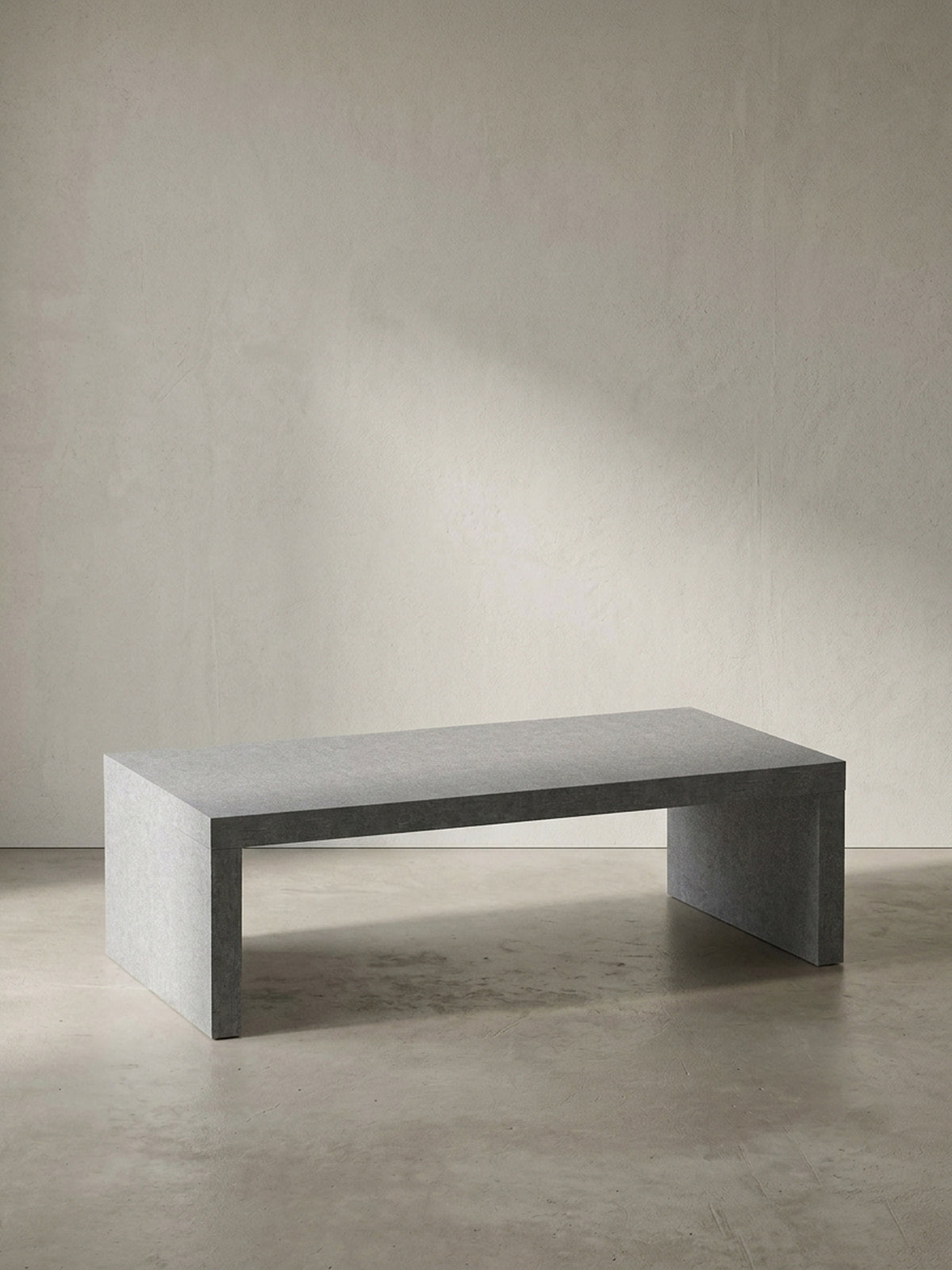 Grauer Couchtisch in klarer Beton-Optik mit den kompakten Maßen 110x55x35 cm frontal vor einem neutralen, reinweißen Hintergrund_